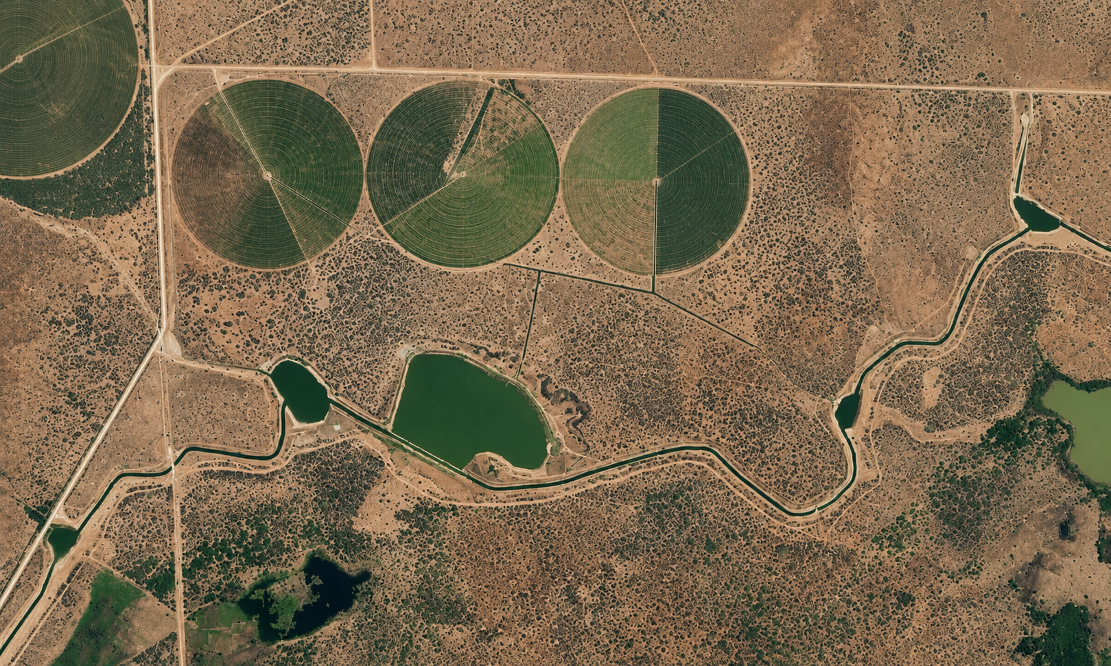 Modern center-pivot sprinkler irrigation in Kenya’s dryland agricultural zone, showing circular irrigated fields, water-storage ponds, and canal alignments that support large-scale food production under the Bura / Galana-Kulalu irrigation development framework.